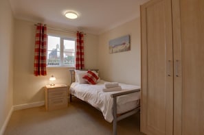 A bedroom with a bed, a nightstand, a lamp, a wardrobe, and a window with curtains. - 4 Bed in Bacton (oc-1990) (Bacton)
