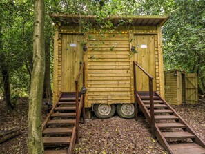 Eine Holzhütte mit einer Rampe zum Eingang, umgeben von Bäumen.