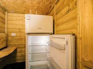 A compact wooden room with a white refrigerator and a white washing machine. - The Moroccan Bell Tent (Newbury)