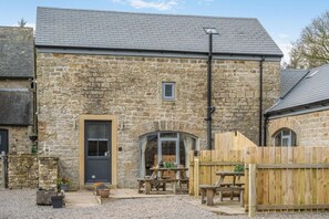A stone building with a dark door, a small window, and a wooden fence. - 3 Bed in Gilsland (oc-f34699) (Waterhead)