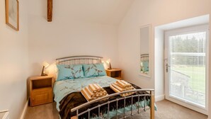 A bedroom with a bed, bedside tables, a mirror, and a door with blinds. - 3 Bed in Gilsland (oc-f34699) (Waterhead)