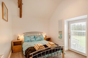 A bedroom with a bed, bedside tables, a mirror, and a door with blinds. - 3 Bed in Gilsland (oc-f34699) (Waterhead)