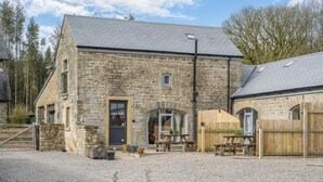 A stone building with a gravel driveway, a wooden fence, and a picnic table. - 3 Bed in Gilsland (oc-f34699) (Waterhead)