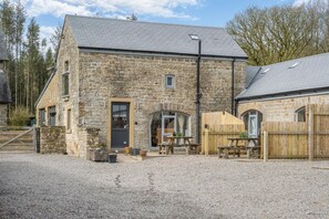 A stone building with a gravel driveway, a wooden fence, and a picnic table. - 3 Bed in Gilsland (oc-f34699) (Waterhead)