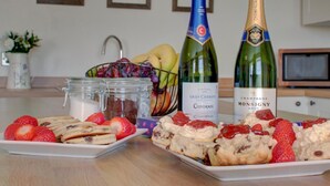 Una mesa con pasteles, fresas y dos botellas de champán.