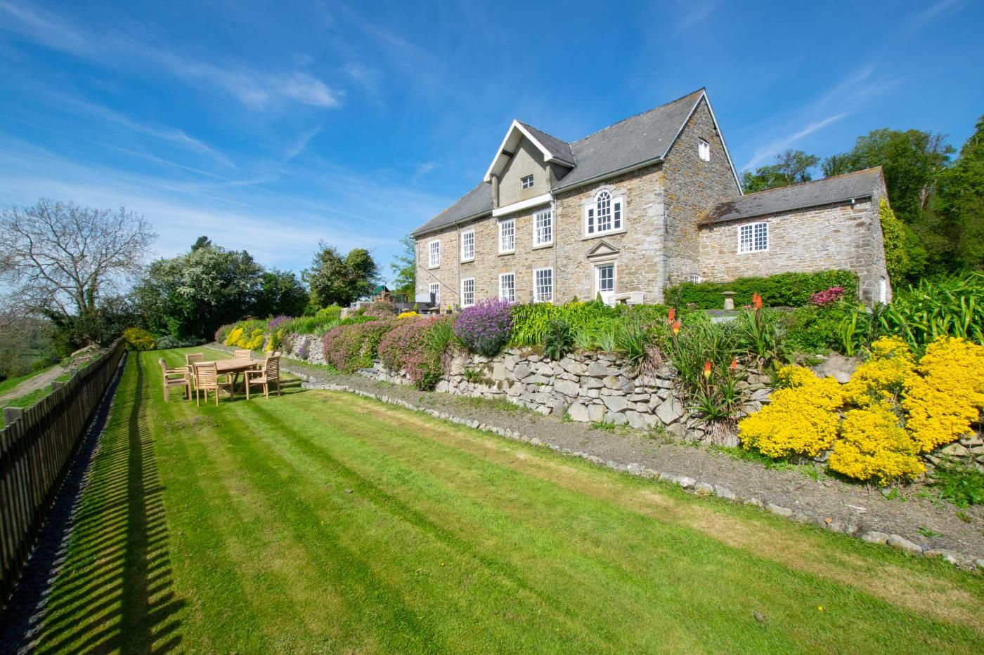 A stone building with a lawn and a wooden fence.