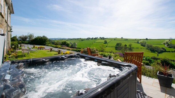 Un jacuzzi en un patio con vistas a campos verdes.