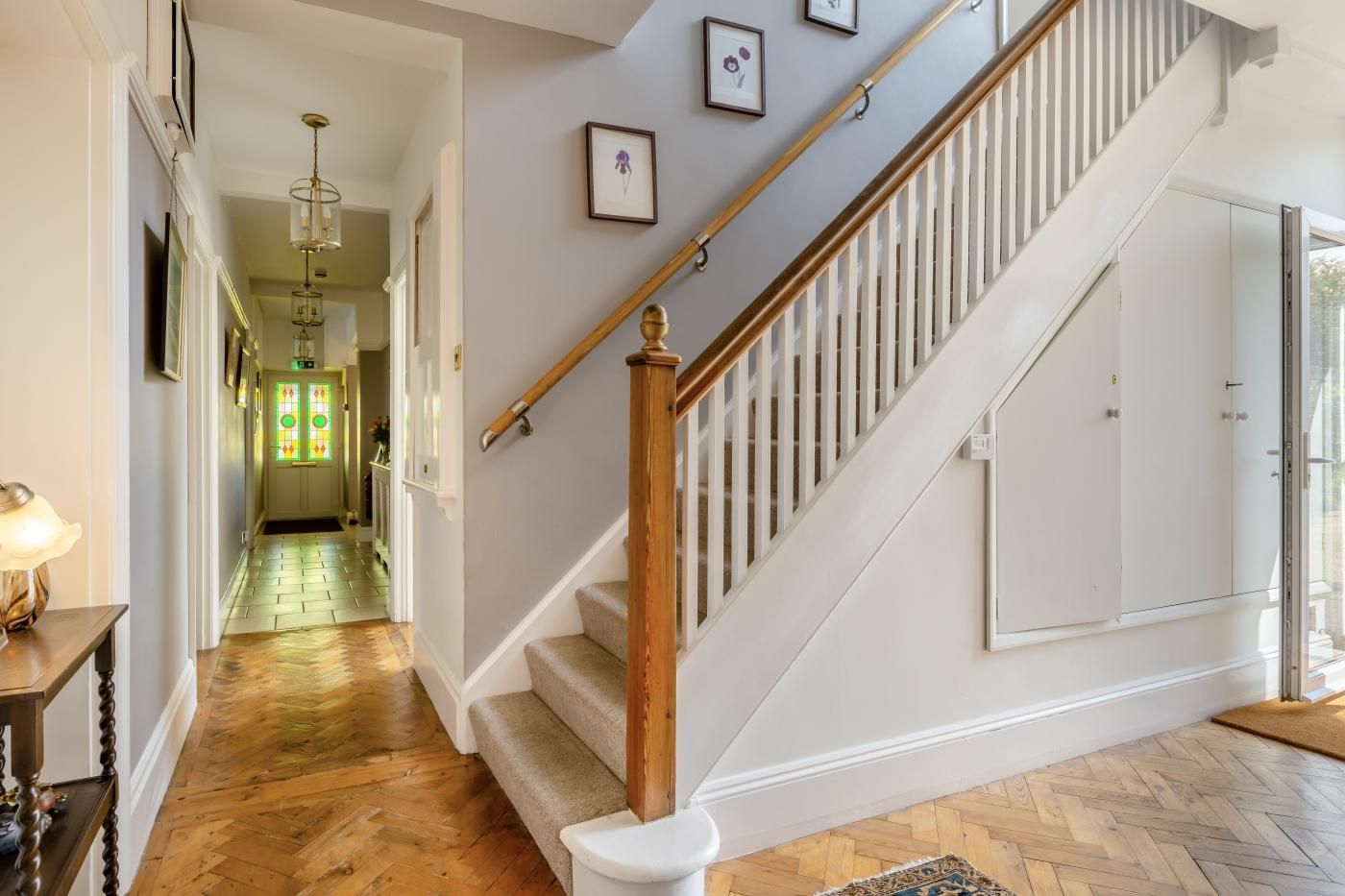 A staircase with a wooden handrail and white balusters, leading to a room with a large window.