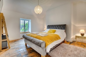 A bedroom with a bed, a window, a chandelier, a nightstand, and a wooden ladder. - 4 Bed in Ruthin (oc-bow136) (Gwyddelwern)