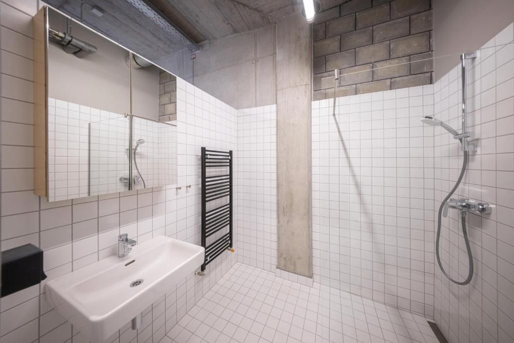 Une salle de bain avec un lavabo blanc, un miroir, un porte-serviettes et un espace douche.