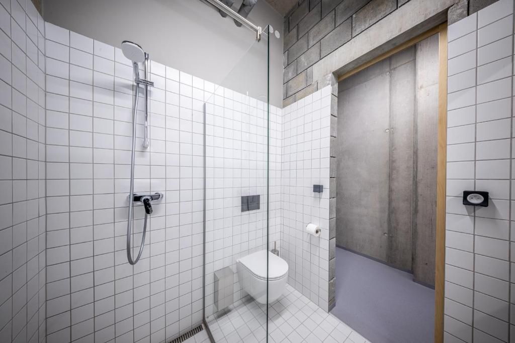Une salle de bain moderne avec une douche à parois de verre, des toilettes blanches et une porte en bois.