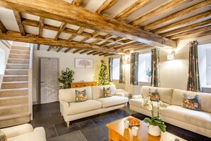 Ein Wohnzimmer mit einer Sofagarnitur, einem Couchtisch und einer Treppe, die in einen anderen Raum führt.