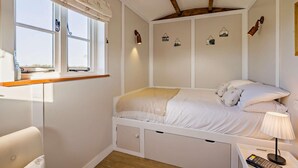 Ein Schlafzimmer mit einem Bett, einem Nachttisch, einer Lampe und einem Fenster mit Vorhängen.