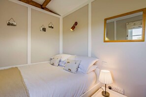 A bedroom with a bed, pillows, a bedside lamp, a mirror, and wall-mounted picture frames. - 1 Bed in Foulsham (oc-j34678) (Foulsham)