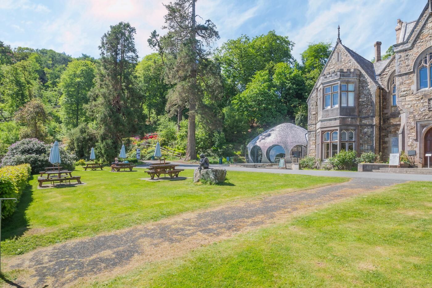 A stone building with a turret, surrounded by a well-maintained lawn and picnic tables.
