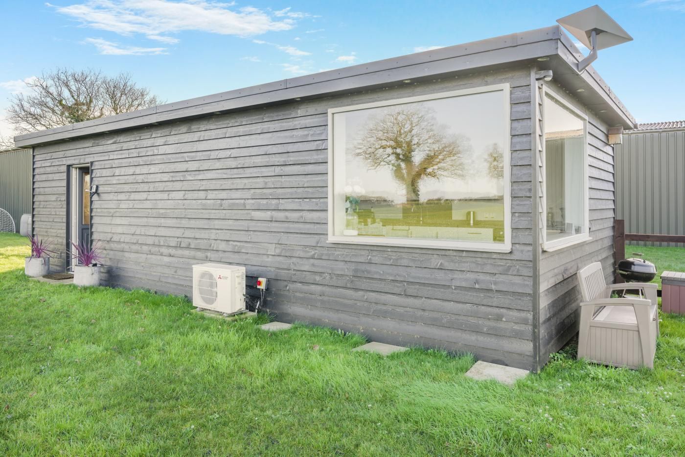 Un petit bâtiment d’un seul étage, doté d’une grande fenêtre, d’une porte et d’un appareil de climatisation.