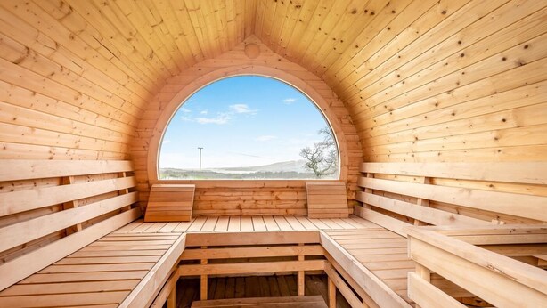 Una sauna de madera con techo semicircular y bancos.