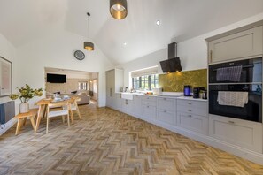 Eine moderne Küche mit Fischgrätparkett, einem Einbauofen und einem Essbereich mit Holztisch und Stühlen.