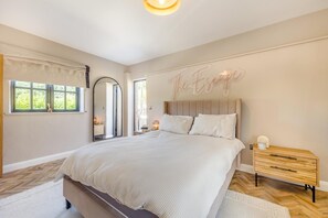 Un dormitorio con una cama grande, una mesita de noche, un espejo y un cartel en la pared.