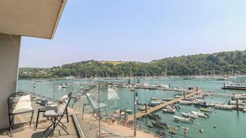 A balcony with a view of a marina, boats, and a hilly landscape.