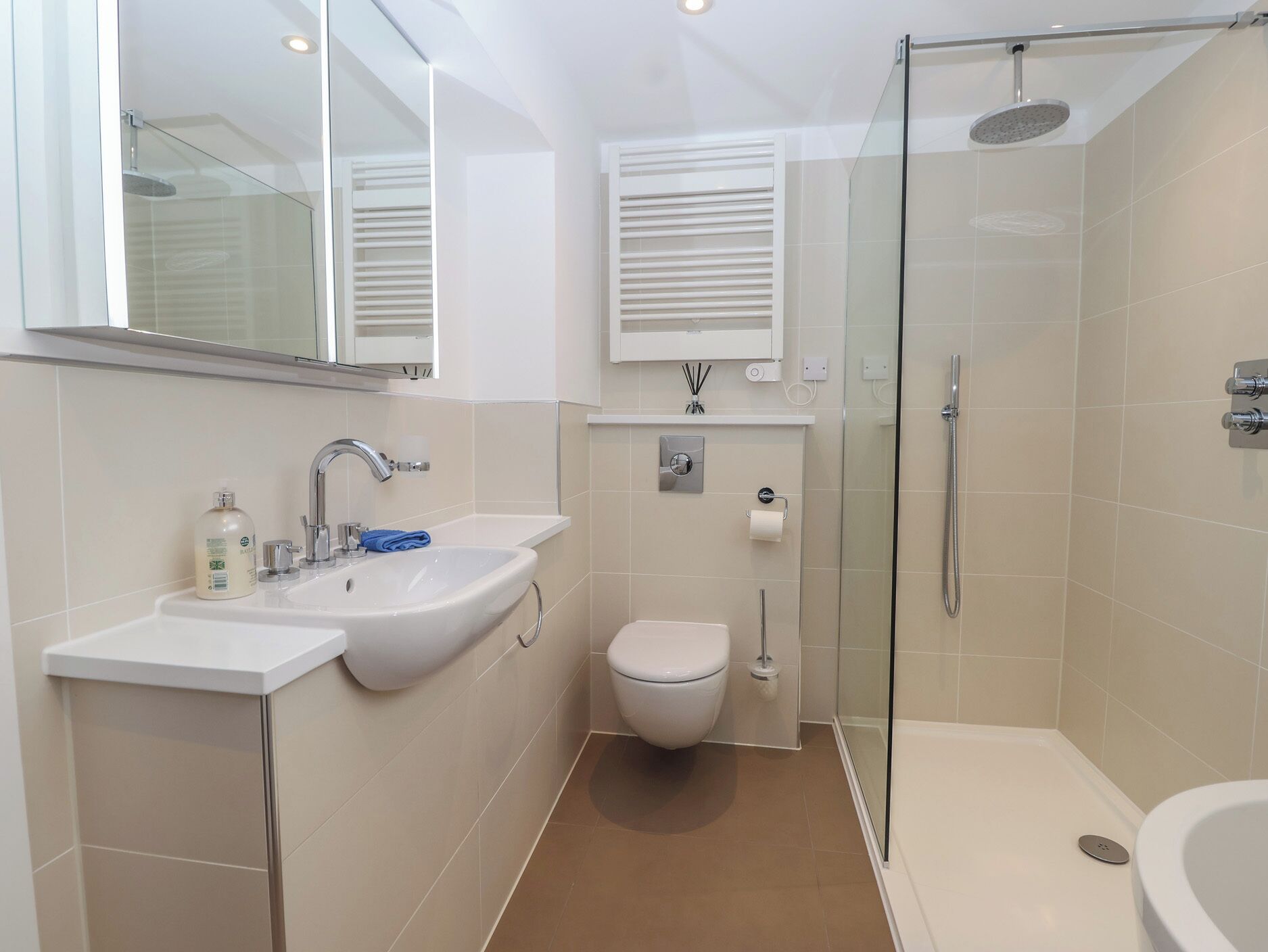A modern bathroom with a glass shower enclosure, a toilet, and two sinks.