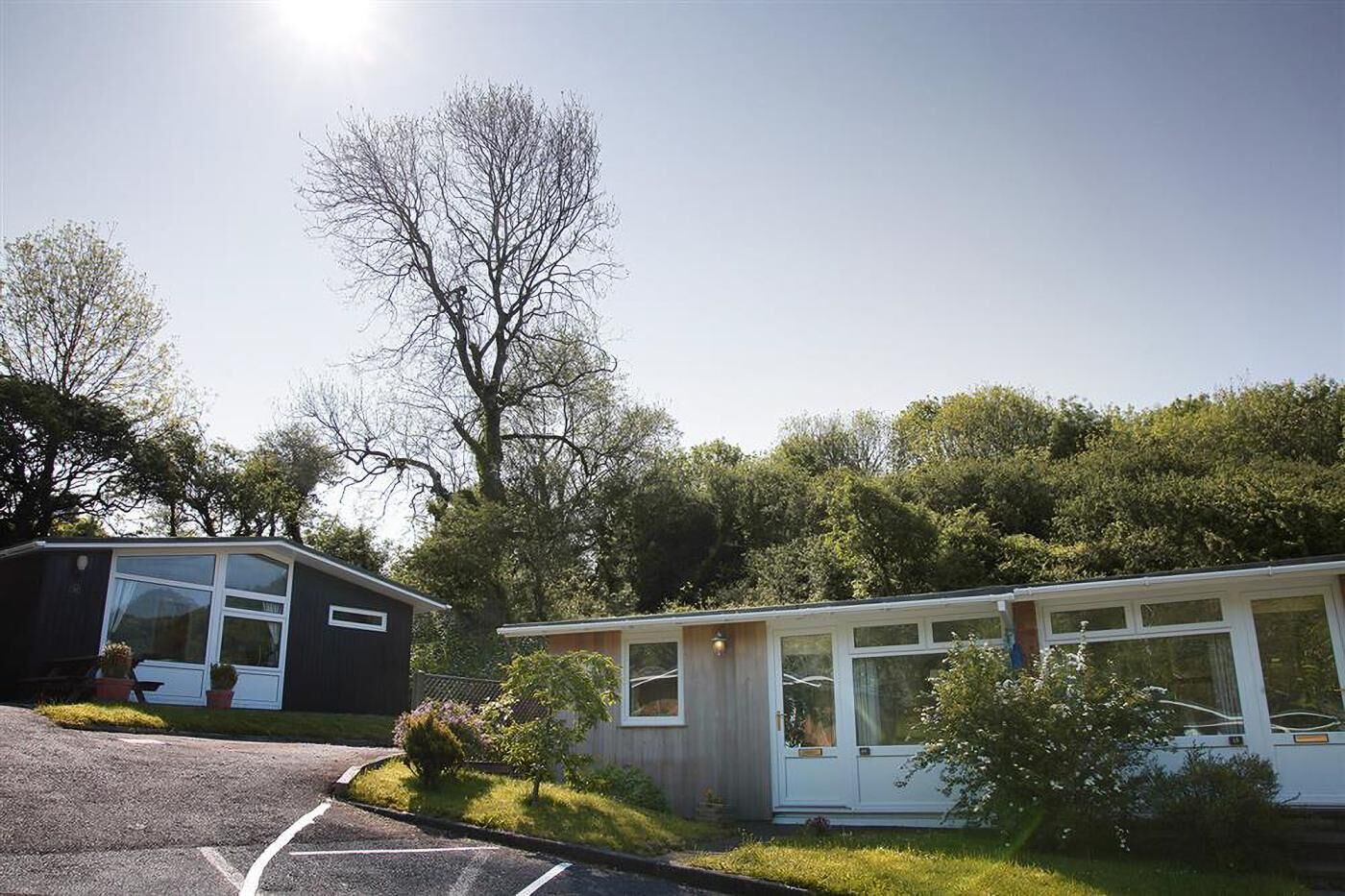 Un petit bâtiment d’un seul étage, doté d’une grande fenêtre et entouré de verdure et d’arbres.