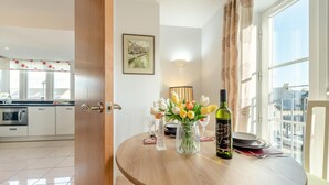 Een moderne keuken met een eethoek, een tafel met een bloevas en een fles wijn.