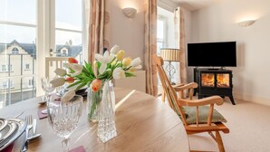 Een eettafel met een vaas tulpen, een lamp en een televisie in een kamer met een open haard.