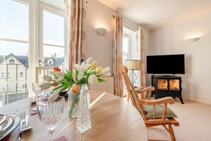 Ein Esstisch mit einer Tulpenvase, einer Lampe und einem Fernseher in einem Raum mit Kamin.