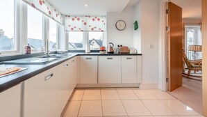 Een moderne keuken met een groot raam, een klok aan de muur en uitzicht op gebouwen.