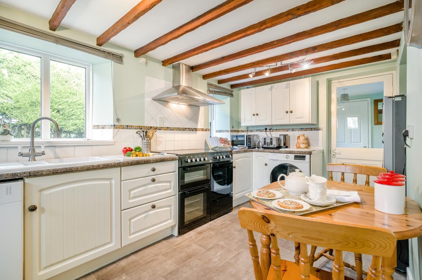 Una cocina con armarios blancos, estufa, horno y una mesa de comedor con una silla.
