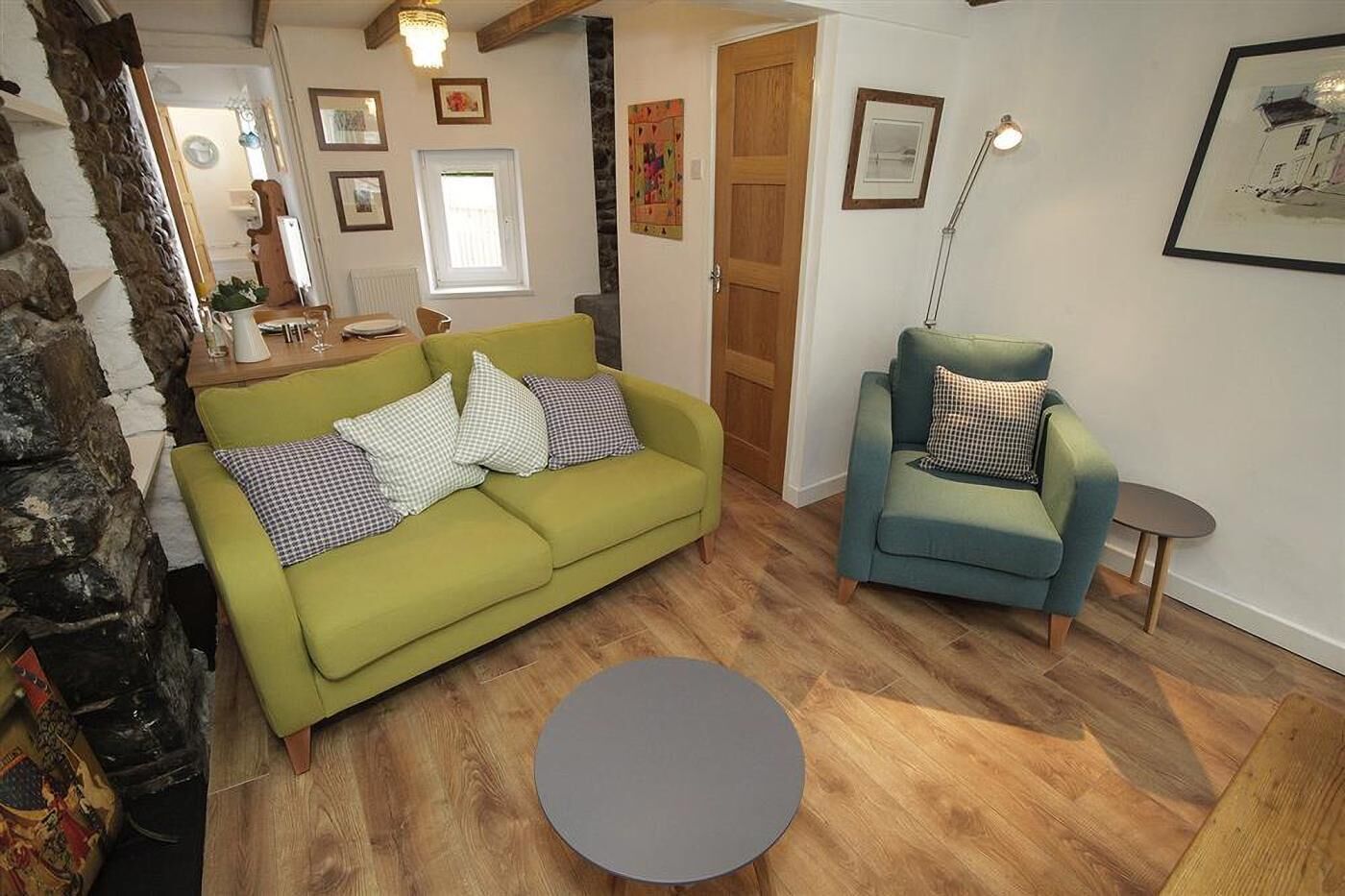 Ein Wohnzimmer mit einem grünen Sofa, einem blauen Sessel, einem runden Couchtisch und einer Steinwand.
