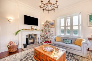 Un salon avec une cheminée, un sapin de Noël, un canapé et une table basse.