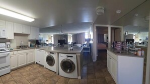 Een compacte keuken met een ingebouwde wasmachine en droger, een klein eethoekje en een kitchenette.