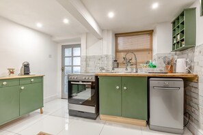 A modern kitchen with a built-in oven, dishwasher, and a window with blinds. - 2 Bed in Buxton (oc-f34153) (Buxton)