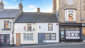 A street view with a building featuring a sign for 'The London Road Inn' and a massage therapy business. - 2 Bed in Buxton (oc-f34153) (Buxton)