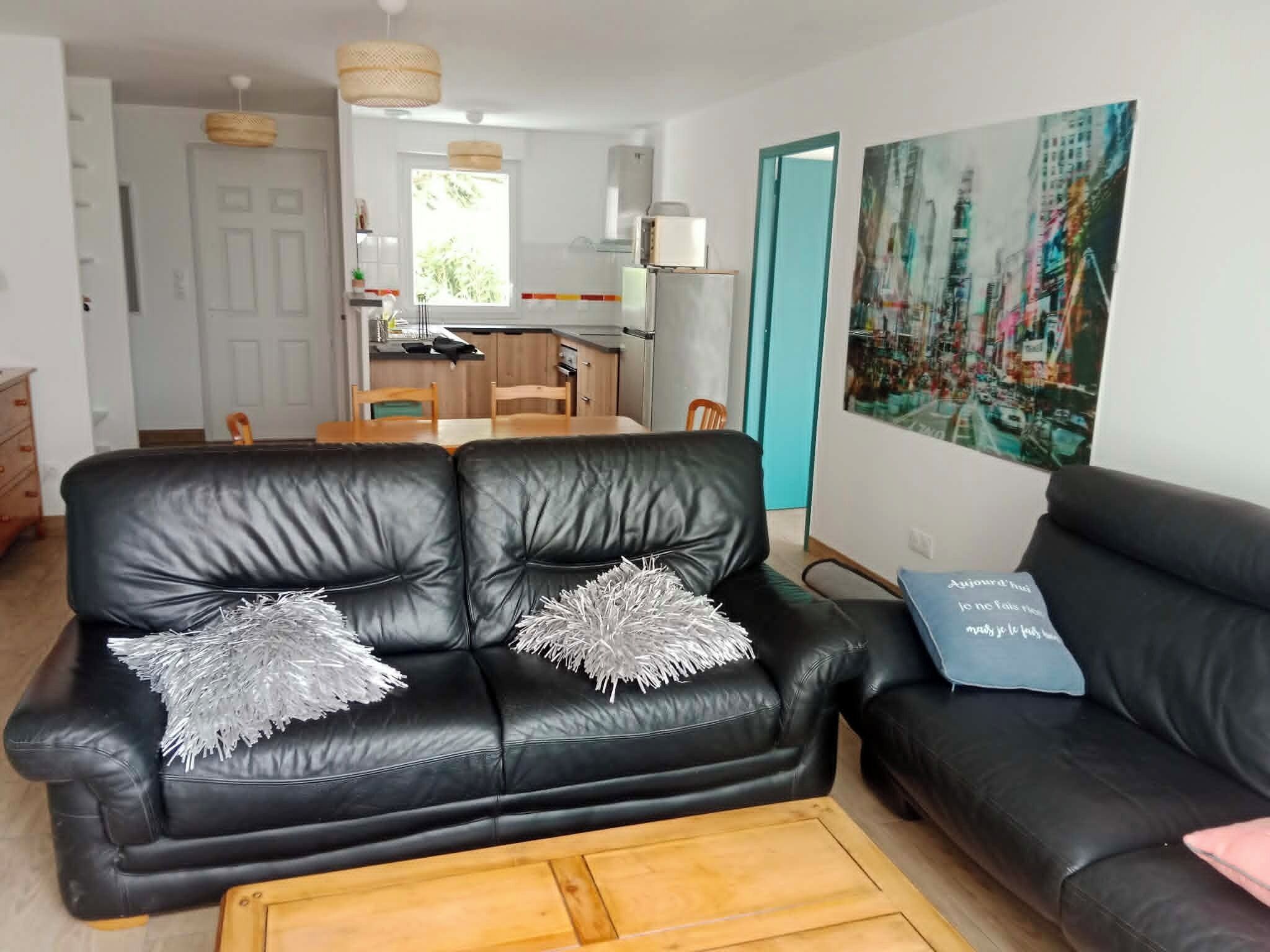 Ein Wohnzimmer mit einem schwarzen Ledersofa, einem Holztisch und einem Stadtbild an der Wand.