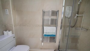Une salle de bain équipée de toilettes, d’une douche et d’un porte-serviettes.