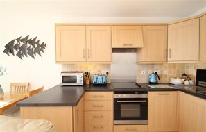 A modern kitchen with wooden cabinets, a microwave, a toaster, and a kettle. - 1 Bed in Caswell (oc-hh9312) (Bishopston)