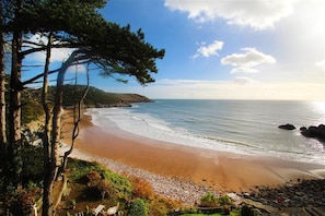 Ein Strand mit felsigem Ufer, blauem Himmel und Blick auf das Meer.
