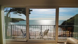Un balcon avec vue sur la mer, une table et deux chaises.