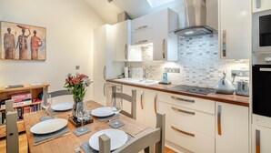 A modern kitchen with white cabinetry, a skylight, and a dining area with a table set for four.
