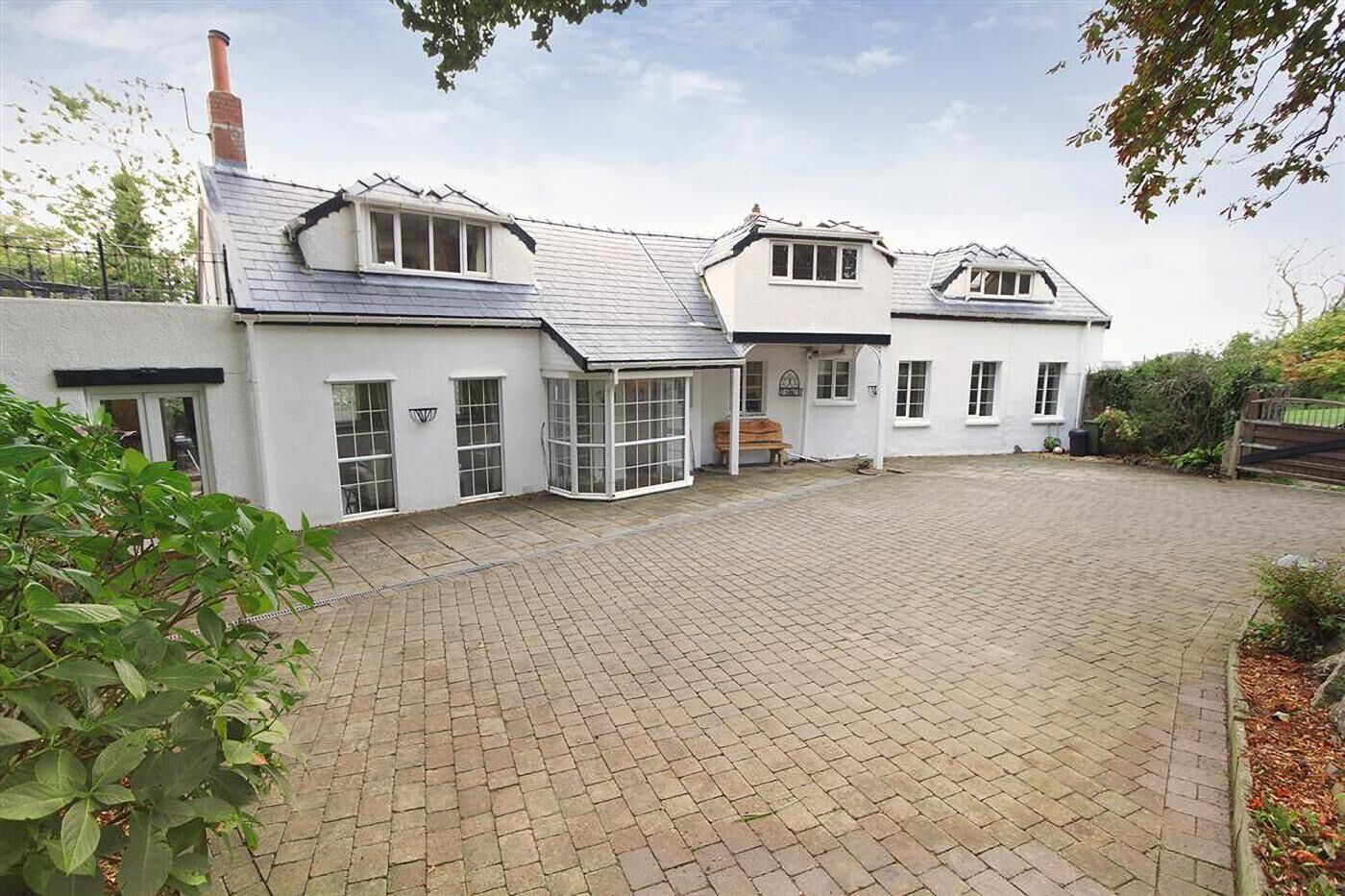 A white building with a tiled driveway and a chimney.