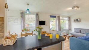 A modern kitchen with a dining area, a sofa, and a television. - 1 Bed in Caswell (oc-hh372) (Newton)