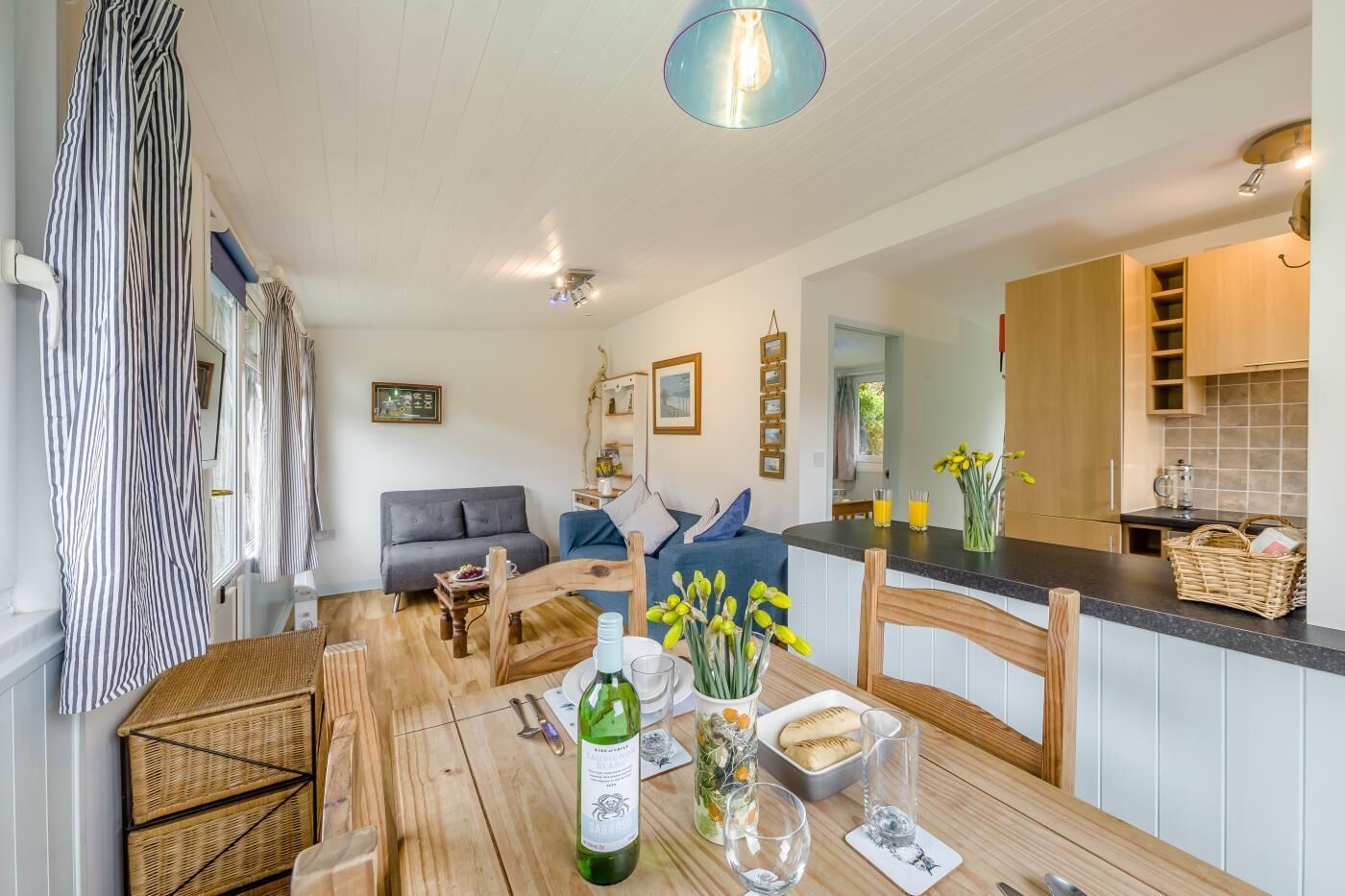 A cozy living area with a wooden dining table, a sofa, and a kitchen area with wooden cabinets.