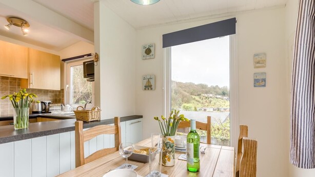 A modern kitchen with a dining area, a view of the countryside, and a window with a view. - 1 Bed in Caswell (oc-hh372) (Newton)