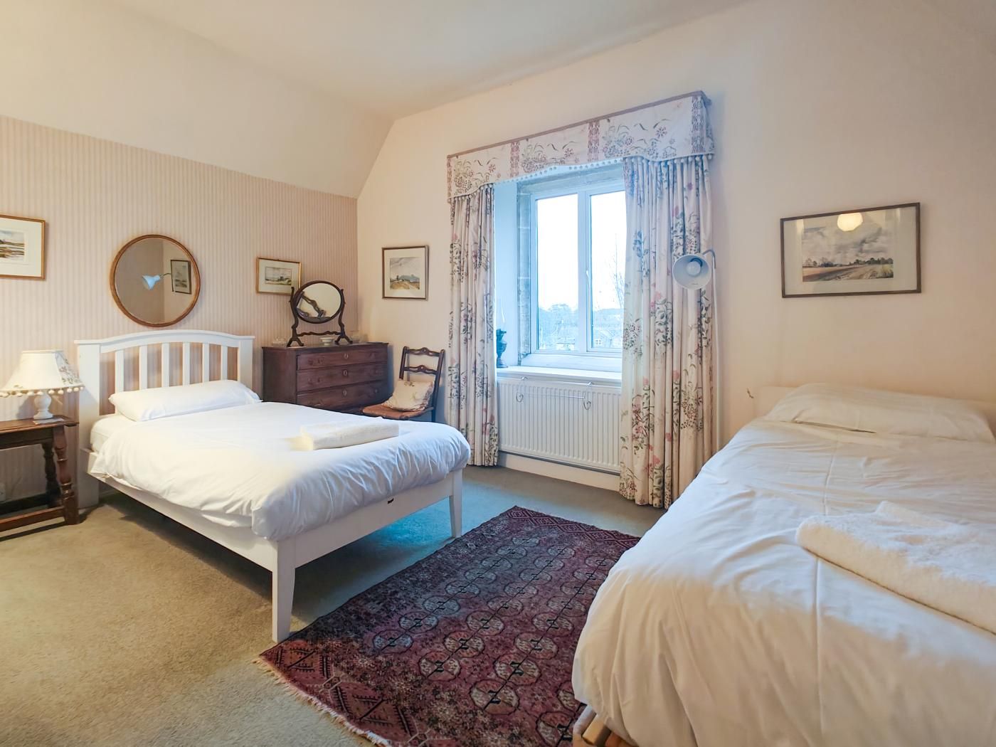 Un dormitorio con dos camas, un aparador, un espejo y una ventana con cortinas.