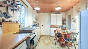 Een kleine keuken met een houten plafond, een eethoek met stoelen en een witte koelkast.