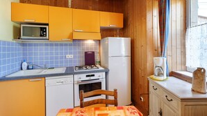 Une cuisine compacte dotée de meubles en bois, d’un four à micro-ondes, d’un réfrigérateur, d’une cuisinière à gaz et d’un évier.