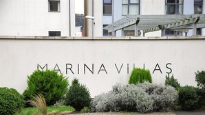 Une enseigne indiquant « MARINAVILLAS », avec une allée pavée et divers arbustes devant.